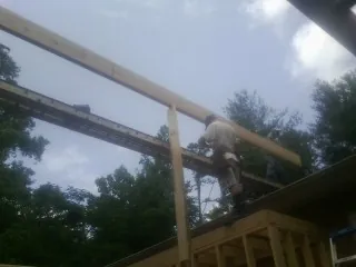Carpenter setting a ridge beam over a new addition frame — Ice Dam Removal by Roofing Brothers in Wirtz