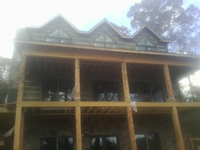 Dormers and porch framing on a large log home under construction — Roof Coating work by our crew in Wirtz