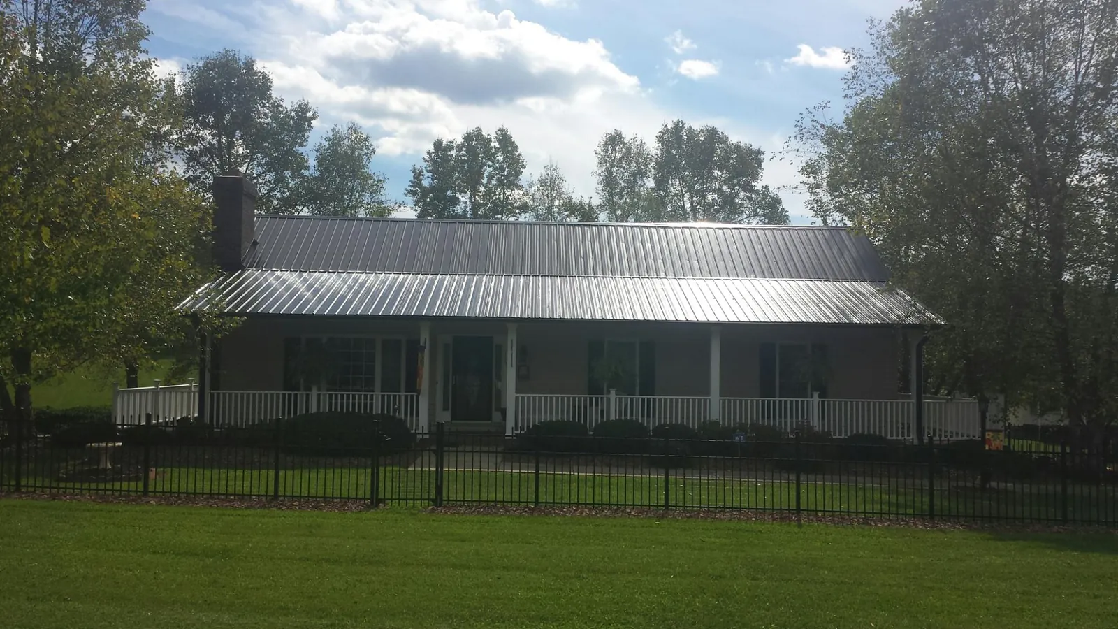 Gray metal roof on a brick ranch with a full width front porch — Gutter Guard Installation work by our crew in Wirtz