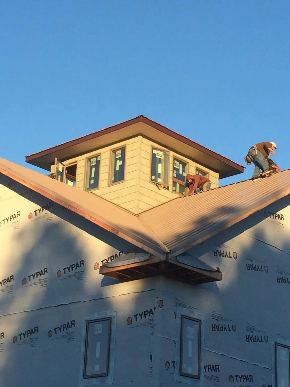 Roofers working around a rooftop cupola on a new metal roof at sunset — Roof Waterproofing in Wirtz by Roofing Brothers
